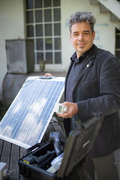 Ein Mann mit einer Solarzelle in der Hand.