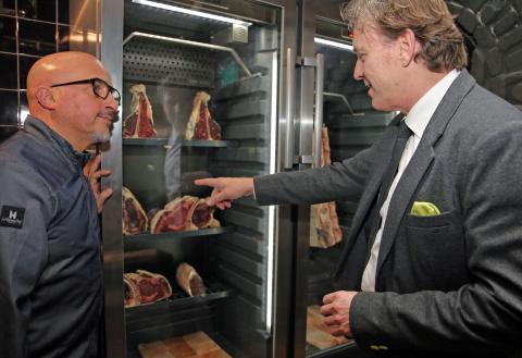 Der Bürgermeister und ein Mann schauen sich Fleisch an.