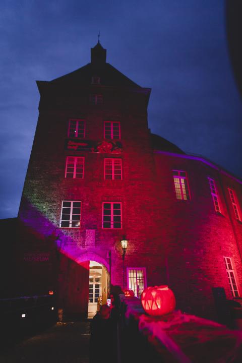 Das Moerser Schloss bunt beleuchtet und ein geschnitzter Kürbis.