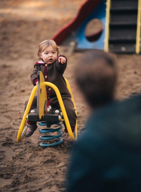 Ein Kind sitzt auf einem Schaukelgerät auf einem Spielplatz