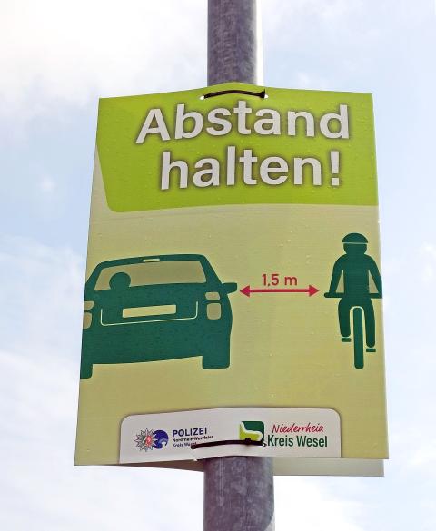 Ein grünes Plakat mit dem Text: Abstand halten! 