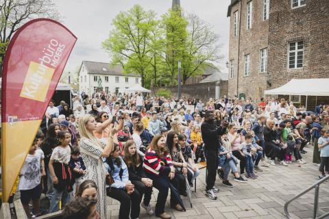 Viele Personen sitzen auf Bänken auf dem Schlossvorplatz.