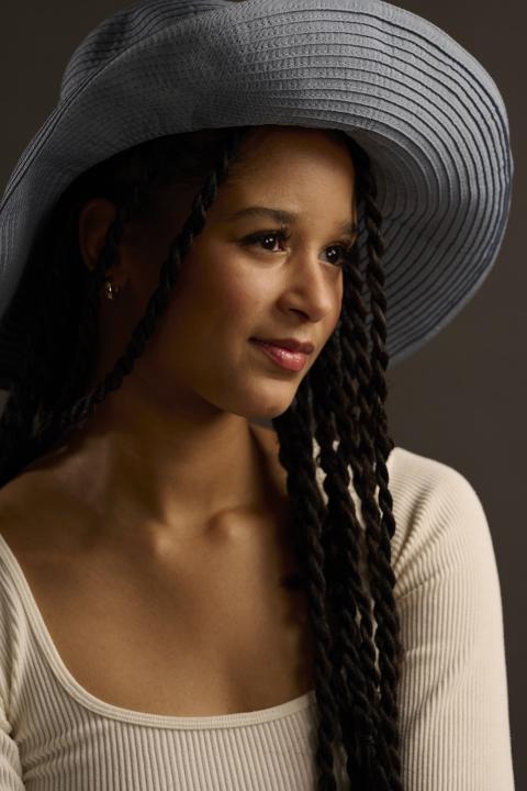 Eine Frau mit einem Hut vor einem schwarzem Hintergrund