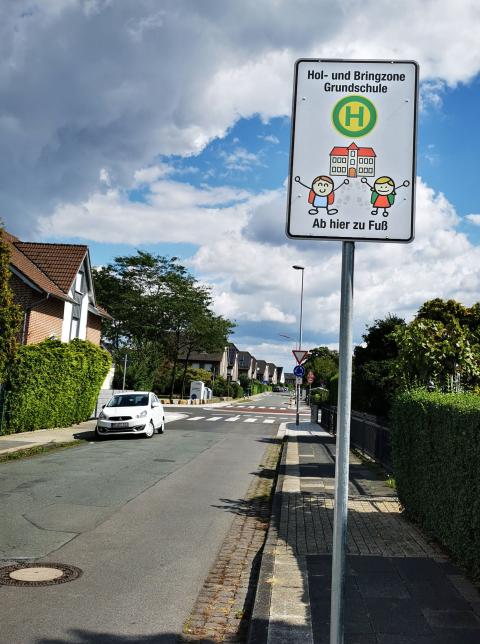 Bild von einem Schild mit Kindern vor einer Schule 