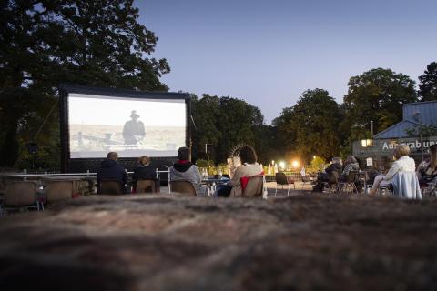 Personen sitzen im Schlosshof und schauen sich einen Film an.