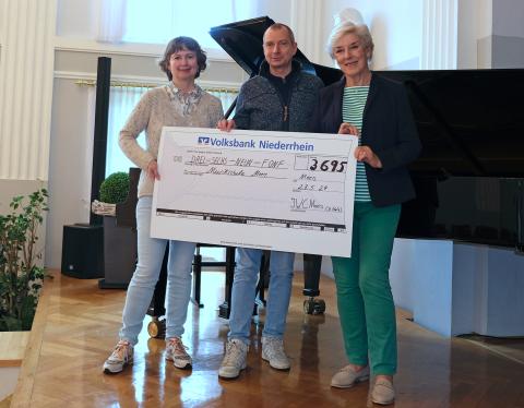 Dr. Babett Götz (l.) und Evelyn Cillis (r.) übergeben den Musikschulleiter Georg Kresimon eine Spende in Höhe von 3.695 Euro.